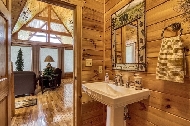 bathroom with wood-type flooring, a skylight, and wooden walls