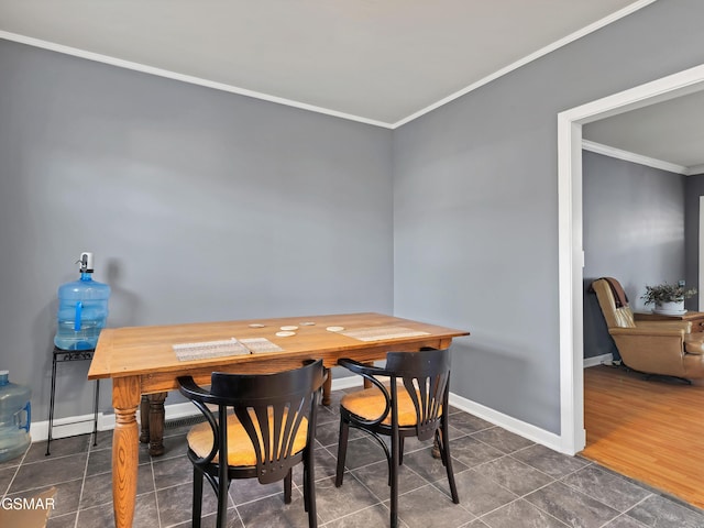 dining space with ornamental molding and dark tile patterned flooring