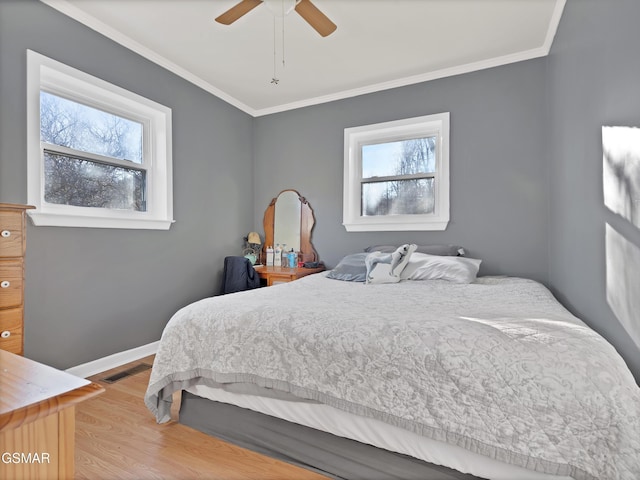 bedroom with multiple windows, ornamental molding, and hardwood / wood-style floors