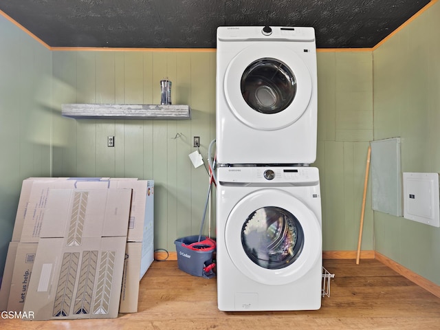 washroom with stacked washing maching and dryer and light hardwood / wood-style flooring