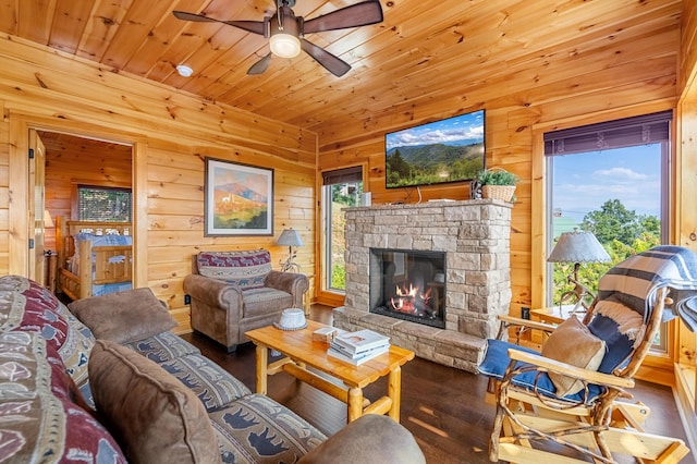 living room with ceiling fan, wood-type flooring, wooden walls, a fireplace, and wood ceiling