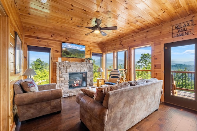 living room with dark hardwood / wood-style flooring, ceiling fan, wooden walls, wooden ceiling, and a fireplace