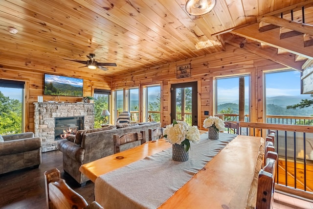 dining space with a mountain view, hardwood / wood-style flooring, ceiling fan, a fireplace, and wood ceiling