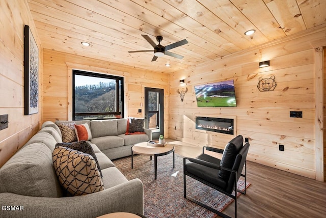 living area with a glass covered fireplace, wood ceiling, recessed lighting, and wood finished floors