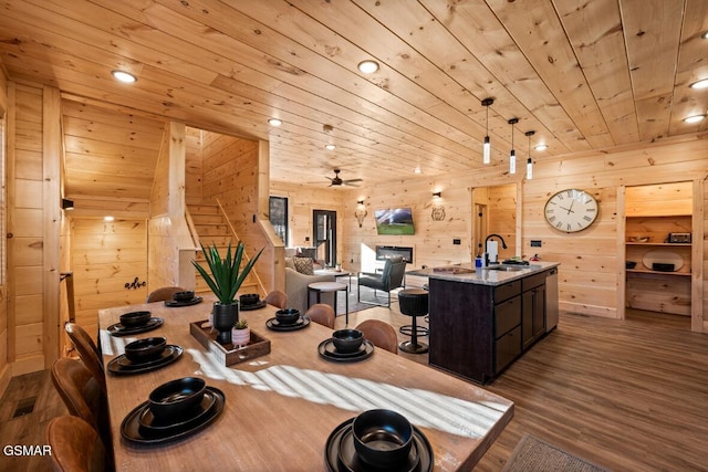 dining room featuring sink, wood ceiling, light hardwood / wood-style flooring, and wood walls