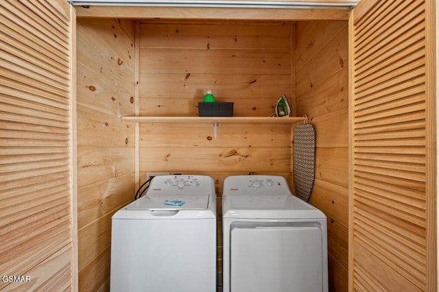 laundry area featuring wooden walls and washing machine and dryer