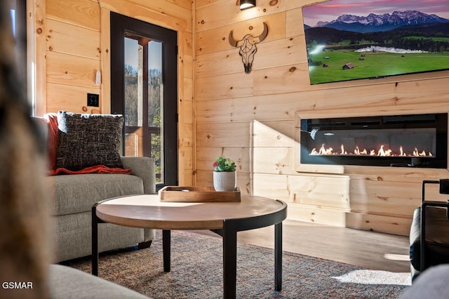 sitting room featuring wood walls, wood finished floors, and a glass covered fireplace