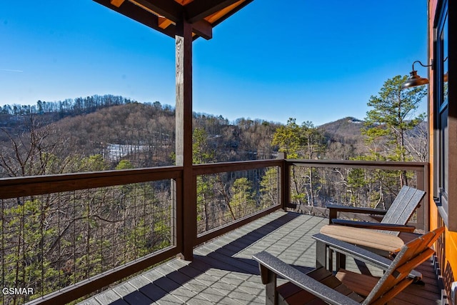 wooden deck with a wooded view and a mountain view