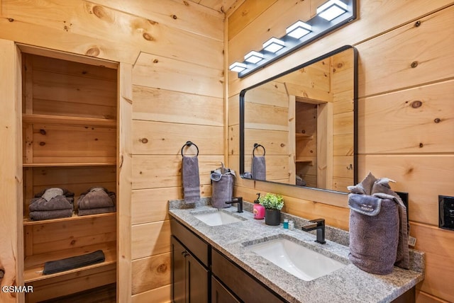 bathroom featuring a sink, wooden walls, and double vanity