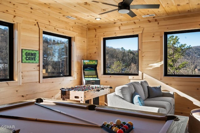 recreation room with wood ceiling, wooden walls, visible vents, and a ceiling fan