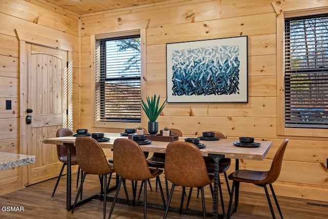 dining room with wood ceiling, wood finished floors, visible vents, and wooden walls