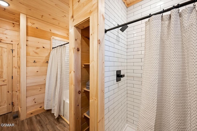 bathroom with wood walls, a shower with shower curtain, and wood finished floors