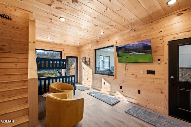 living area featuring hardwood / wood-style floors, wooden ceiling, and wood walls