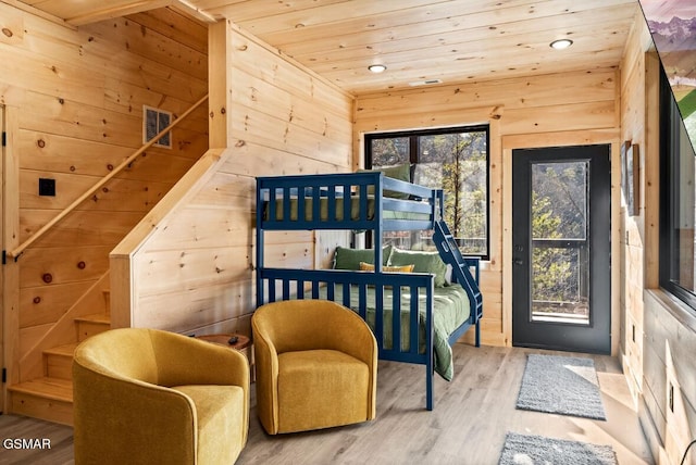 bedroom featuring visible vents, wood walls, wood ceiling, and light wood-style floors