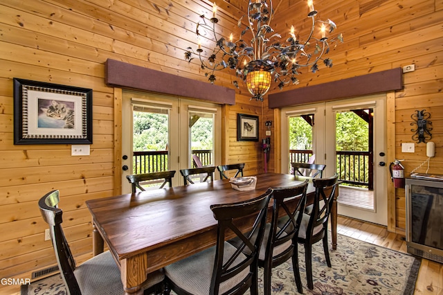 dining room featuring french doors, wood walls, and light wood-style flooring