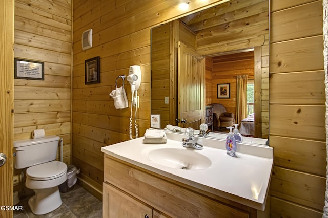 bathroom with vanity, wood walls, and toilet