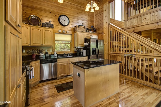kitchen featuring wood walls, a kitchen island, a high ceiling, a sink, and stainless steel appliances