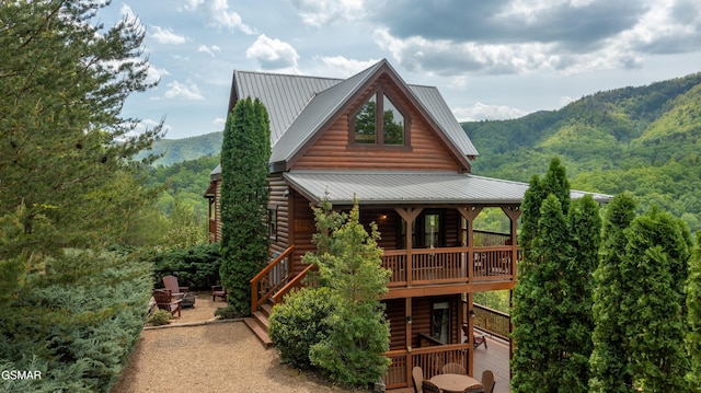 back of property featuring faux log siding, a deck with mountain view, and metal roof