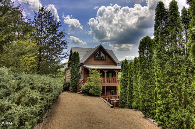 view of front facade with stairs, a porch, metal roof, and log veneer siding