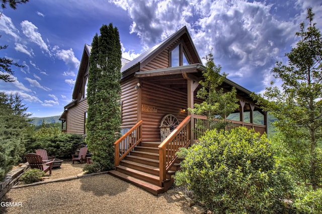 view of front of property featuring an outdoor fire pit, log veneer siding, and metal roof