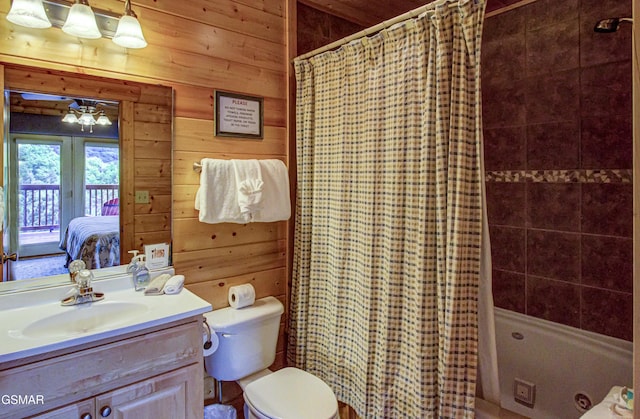 full bath featuring wooden walls, vanity, shower / tub combo with curtain, toilet, and ensuite bath
