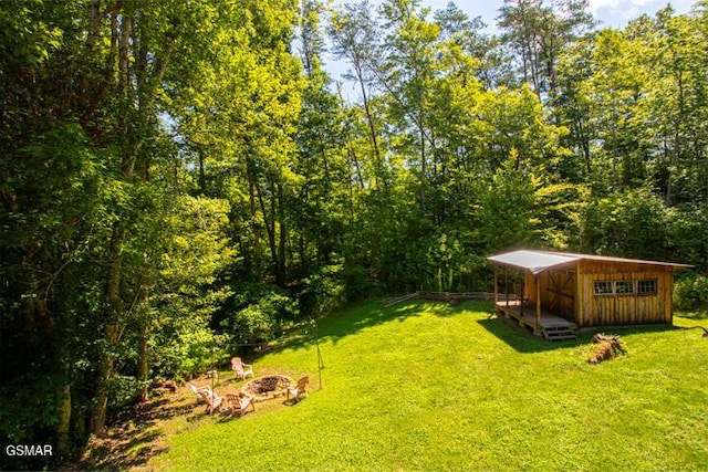 3637 Marshall Ln, Sevierville, TN 37862 - view of grassy yard featuring a fire pit, a storage unit, and a forest view
