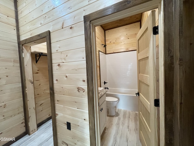 bathroom featuring wooden walls, vanity, wood-type flooring, and toilet