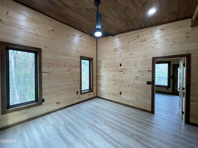 empty room featuring ceiling fan, wood walls, wood-type flooring, and wooden ceiling