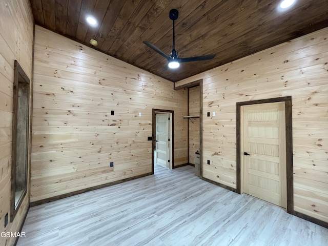 empty room with ceiling fan, wooden ceiling, light hardwood / wood-style floors, lofted ceiling, and wooden walls