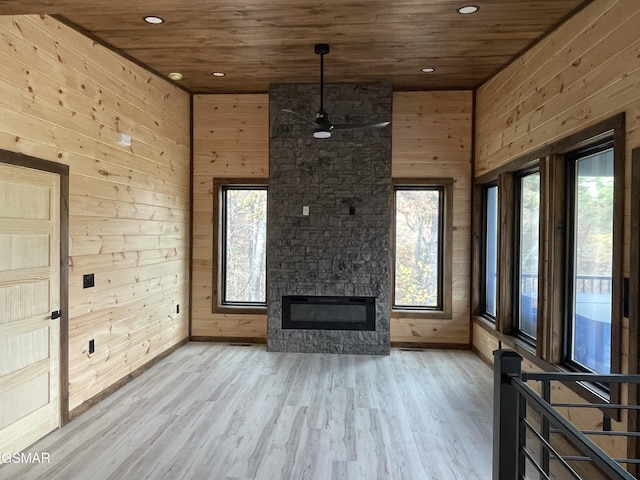 unfurnished living room featuring wood walls, a fireplace, wood ceiling, and light hardwood / wood-style flooring