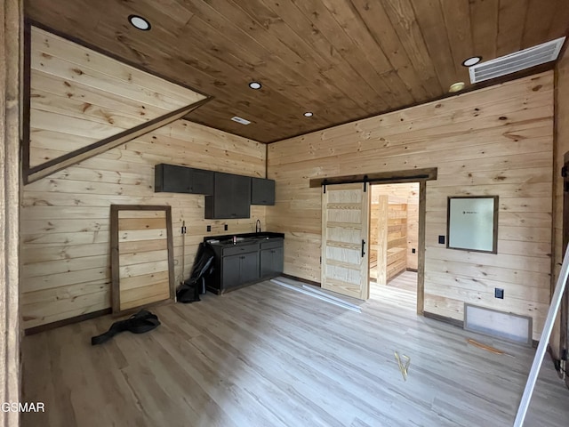 kitchen featuring hardwood / wood-style flooring, a barn door, wooden ceiling, and wooden walls