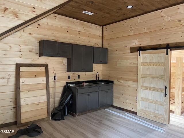 kitchen with light wood-type flooring, sink, wood walls, and wood ceiling