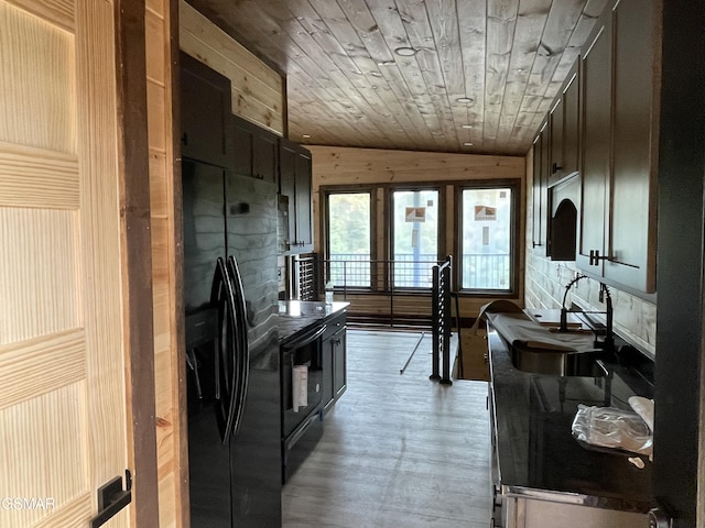 kitchen featuring wood ceiling, sink, black appliances, hardwood / wood-style floors, and wood walls