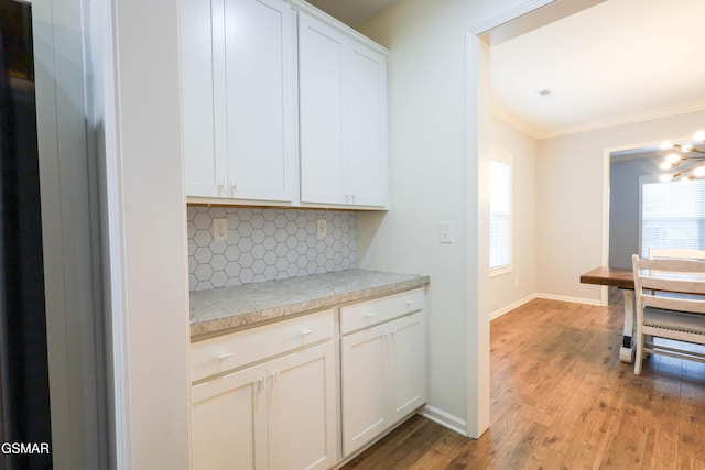 bar featuring white cabinets, crown molding, light hardwood / wood-style flooring, and tasteful backsplash