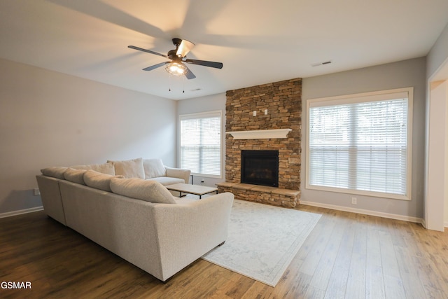 living room featuring a fireplace, wood finished floors, visible vents, and baseboards