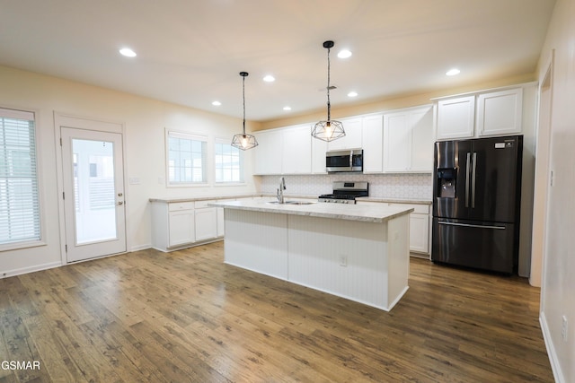 kitchen with white cabinetry, stainless steel appliances, dark hardwood / wood-style flooring, pendant lighting, and a center island with sink