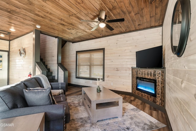 living area with wood ceiling, ceiling fan, a fireplace, wood finished floors, and stairs