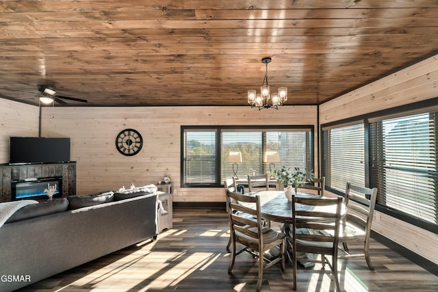 dining space with wood ceiling, ceiling fan with notable chandelier, wood walls, and dark wood-type flooring