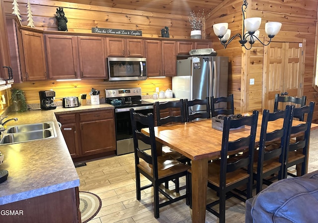 kitchen featuring sink, wooden ceiling, stainless steel appliances, an inviting chandelier, and wood walls