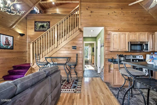 kitchen featuring wooden ceiling, high vaulted ceiling, hardwood / wood-style flooring, light brown cabinetry, and appliances with stainless steel finishes