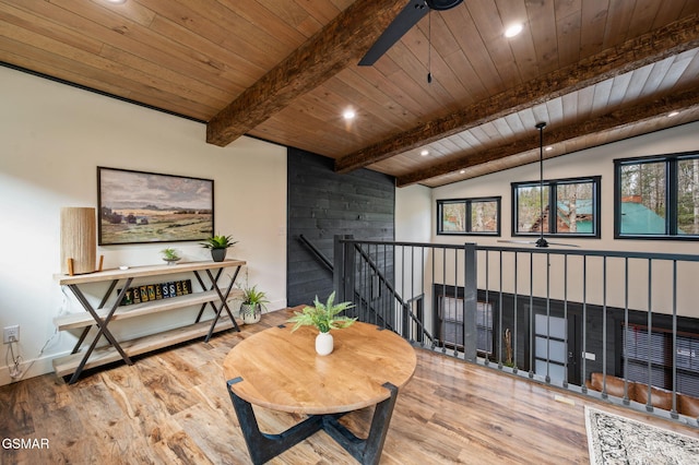 living area featuring a ceiling fan, wooden ceiling, wood finished floors, vaulted ceiling with beams, and an upstairs landing