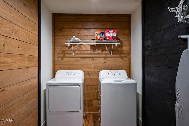 clothes washing area featuring laundry area, wood walls, and separate washer and dryer