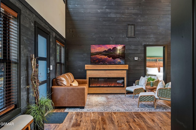 sitting room with a wealth of natural light, a glass covered fireplace, a high ceiling, and wood finished floors