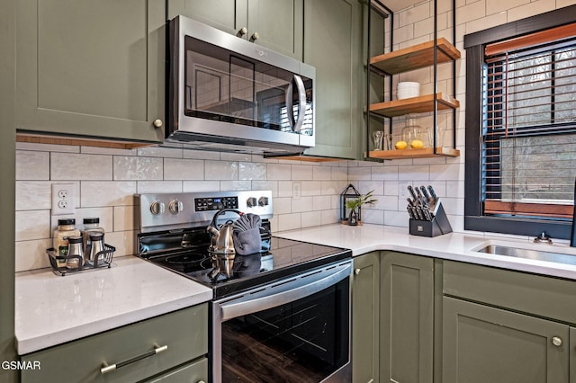 kitchen with stainless steel appliances, backsplash, and green cabinetry