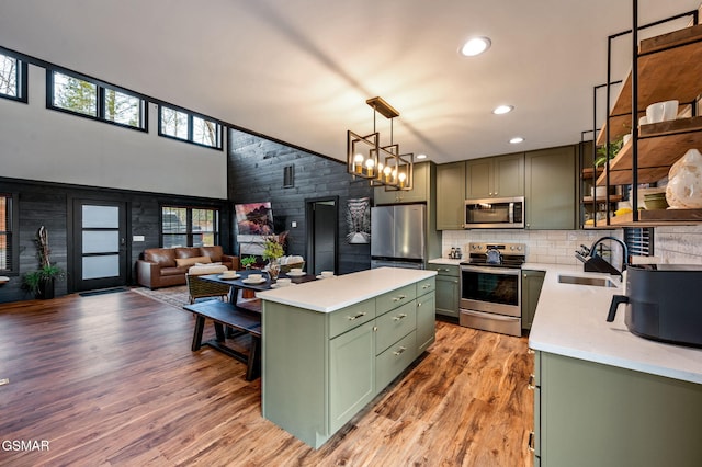 kitchen featuring light wood finished floors, light countertops, appliances with stainless steel finishes, a sink, and green cabinetry