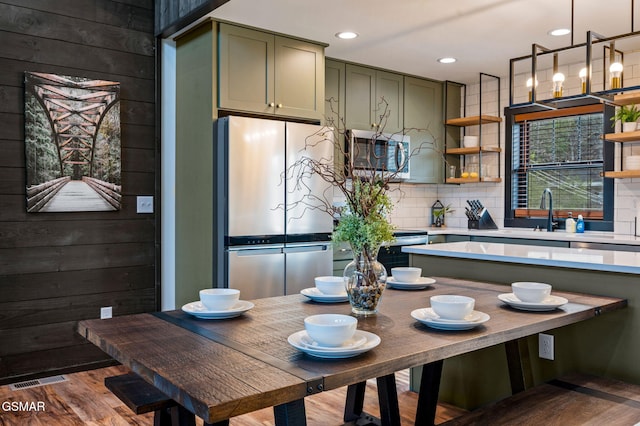 kitchen featuring appliances with stainless steel finishes, light countertops, wooden walls, and open shelves