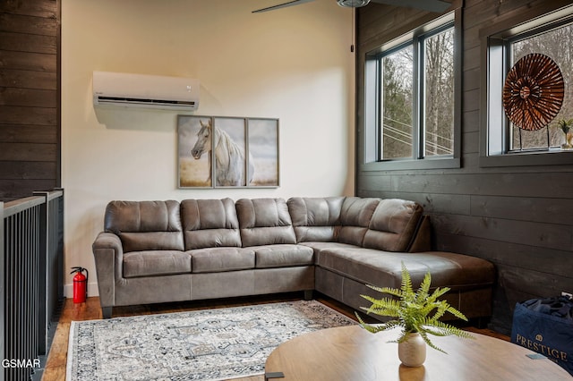 living area with a wall unit AC, wooden walls, and wood finished floors