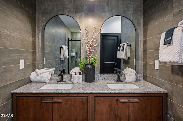 full bathroom with double vanity, a sink, and tile walls