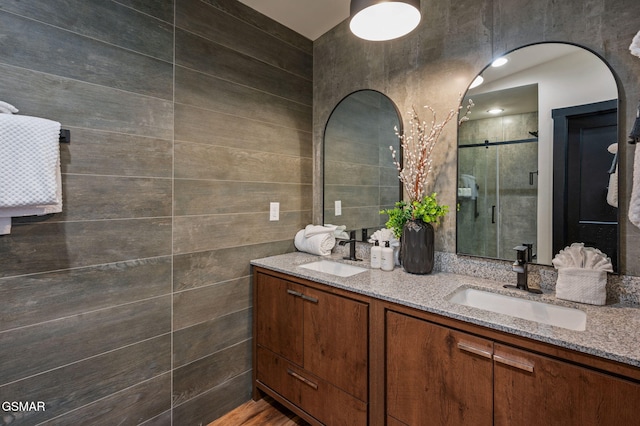 full bath with double vanity, a stall shower, and a sink