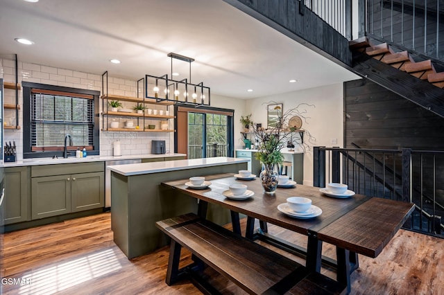 kitchen featuring light wood finished floors, tasteful backsplash, a sink, light countertops, and green cabinetry